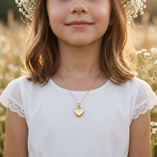 Mädchen trägt goldenes Herz-Medaillon Pure Moyen an feiner Kette, weißes Kleid mit Spitze, Blumenkranz im Haar
