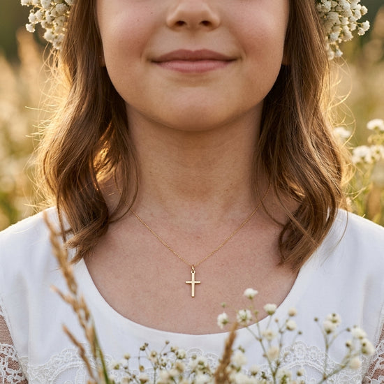 Goldener Kreuz-Anhänger Spirit an zarter Kette, getragen von junger Frau in weißem Kleid mit Blumenkranz