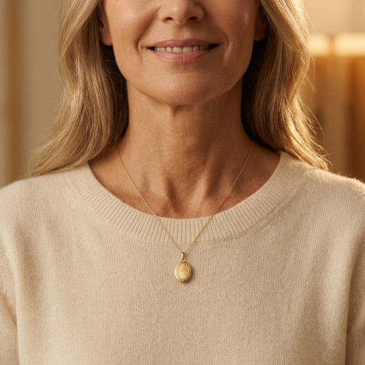 Frau trägt goldenes Oval-Medaillon Willow an feiner Kette, strukturierte Oberfläche, über beigem Pullover