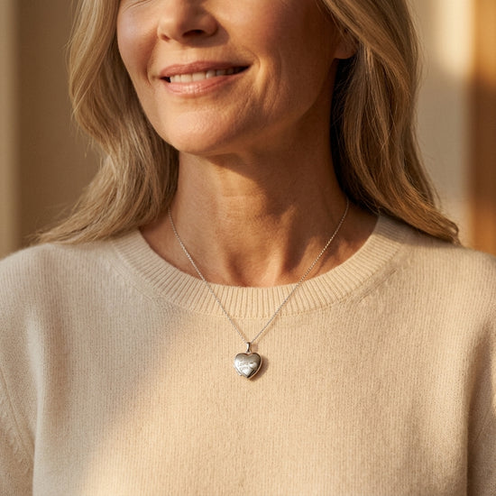 Frau trägt silbernes Herz-Medaillon mit I love you Gravur an feiner Kette über beigem Pullover