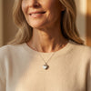 Frau trägt silbernes Herz-Medaillon mit I love you Gravur an feiner Kette über beigem Pullover
