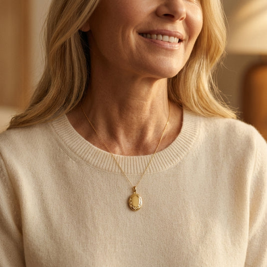 Frau trägt goldenes Oval-Medaillon Ivy mit zartem Blattdekor an feiner Kette über cremefarbenem Pullover