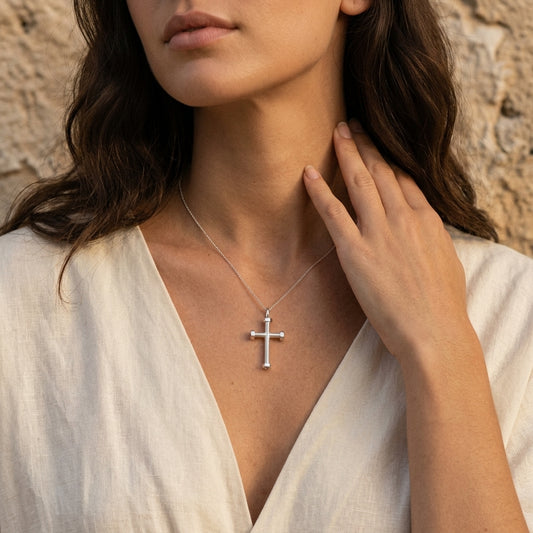 Frau trägt silbernen Kreuz-Anhänger mit hexagonalem Design an feiner Kette, weißes Leinenhemd, natürlicher Look