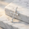 Silberner Kreuz-Anhänger mit Hexagon-Schraubenmuster auf weißem Marmor, poliertes Edelmetall mit strukturierter Oberfläche