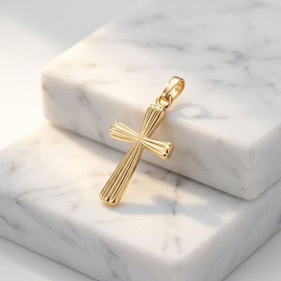 Goldener Kreuz-Anhänger mit gerillter Oberfläche auf weißem Marmor, handgefertigt aus 585er Gelbgold