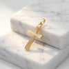 Goldener Kreuz-Anhänger mit gerillter Oberfläche auf weißem Marmor, handgefertigt aus 585er Gelbgold