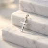 Silberner Kreuz-Anhänger Holy auf weißen Marmorstufen, poliertes Edelmetall mit klassischer Form und Öse