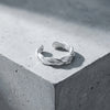 Silberner Ring Breeze mit gedrehtem Design auf grauer Betonoberfläche, offene Form, handgefertigt aus 925er Sterlingsilber