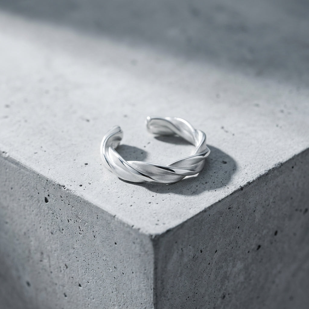 Silberner Ring Breeze mit gedrehtem Design auf grauer Betonoberfläche, offene Form, handgefertigt aus 925er Sterlingsilber