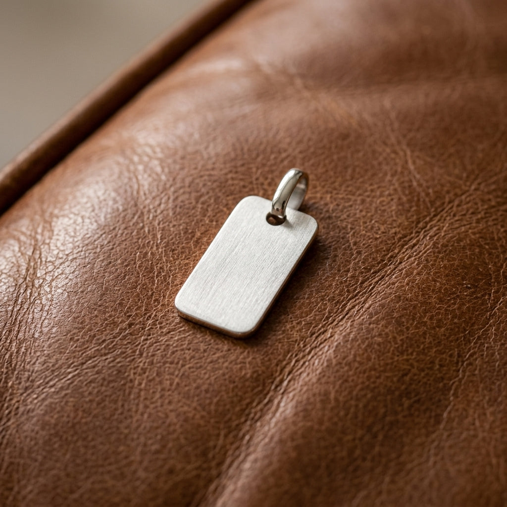 Rechteckiger Silberanhänger mit gebürsteter Oberfläche auf braunem Leder, minimalistisches Design der Aurevia Manufaktur