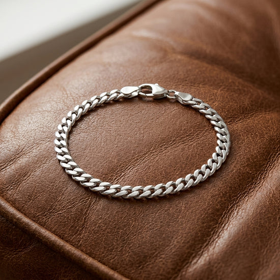 Silbernes Cuba Chain Armband Pedro mit massiven Gliedern und Karabinerverschluss auf braunem Leder
