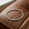 Silbernes Cuba Chain Armband Pedro mit massiven Gliedern und Karabinerverschluss auf braunem Leder