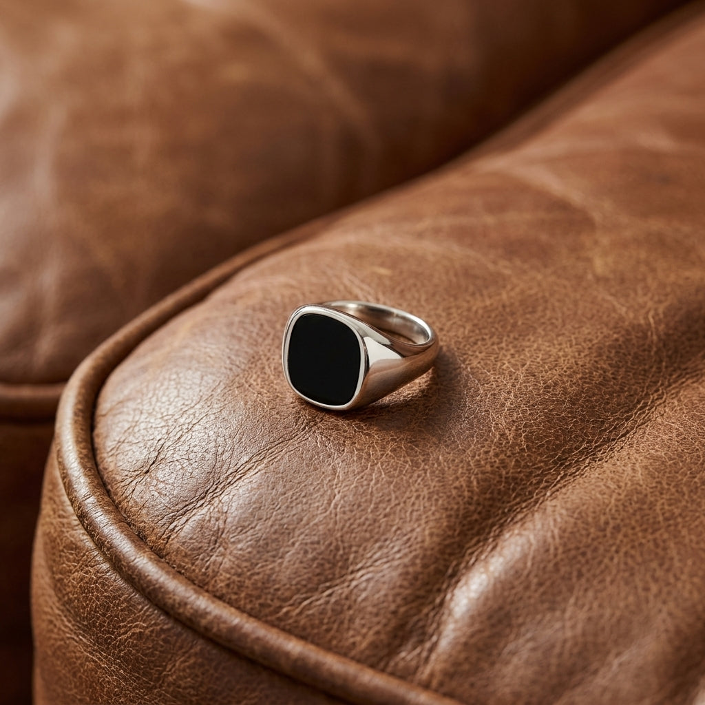 Silberner Siegelring mit schwarzem Onyx auf braunem Leder, eckige Form mit abgerundeten Kanten