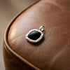Silberner Anhänger mit schwarzem Onyx in Schrauben-Design auf braunem Leder
