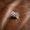 Silberner Bead-Anhänger Reed mit wellenförmiger Oberflächenstruktur auf braunem Leder