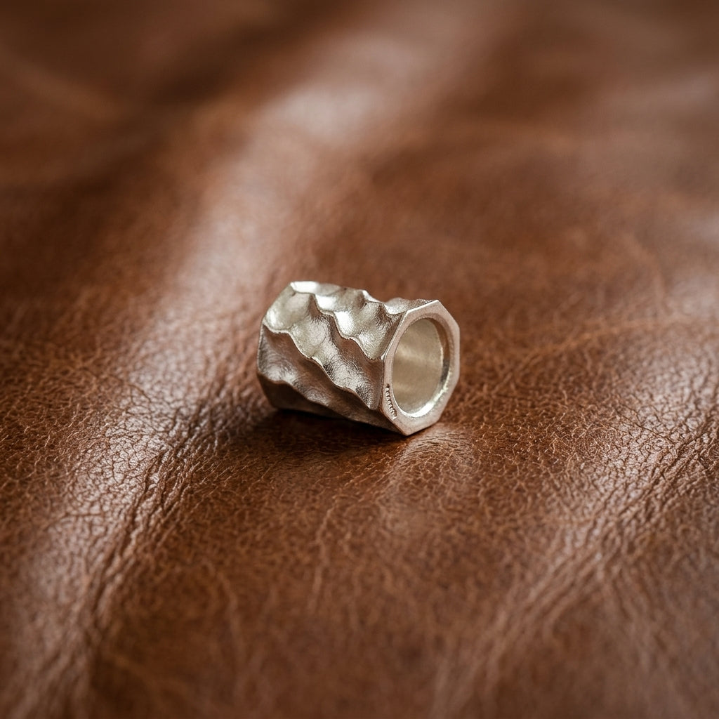 Silberner Bead-Anhänger Reed mit wellenförmiger Oberflächenstruktur auf braunem Leder