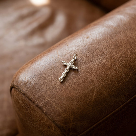Silberner Kreuz-Anhänger mit gedrehter Kettenstruktur auf braunem Leder, handgefertigt von Aurevia Manufaktur