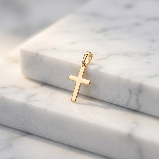 Goldener Kreuz-Anhänger Essence Petit mit polierter Oberfläche auf weißem Marmor, handgefertigt aus 585er Gold