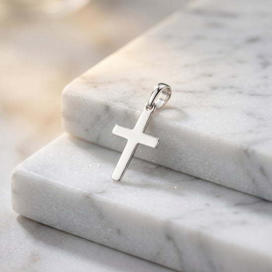 Silberner Kreuz-Anhänger Essence Petit auf weißem Marmor, polierte Oberfläche, minimalistisches Design aus 925er Sterlingsilb