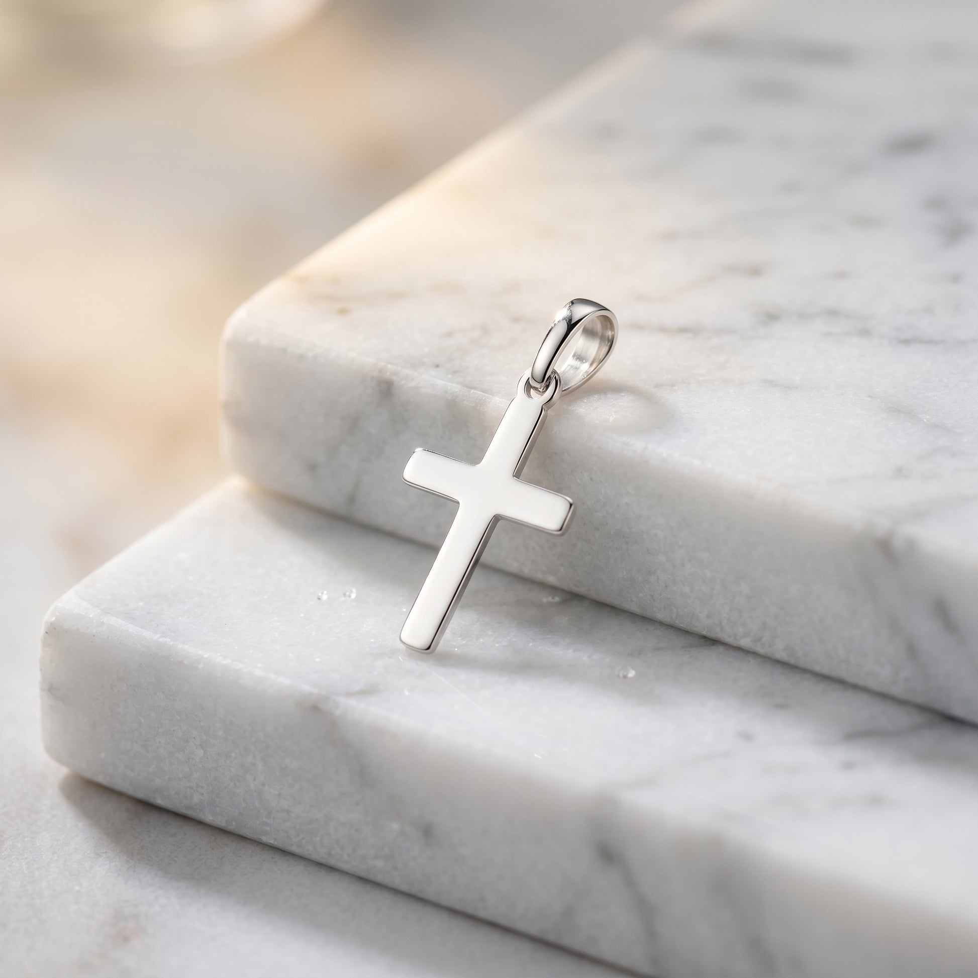 Silberner Kreuz-Anhänger Essence Petit auf weißem Marmor, polierte Oberfläche, minimalistisches Design aus 925er Sterlingsilb