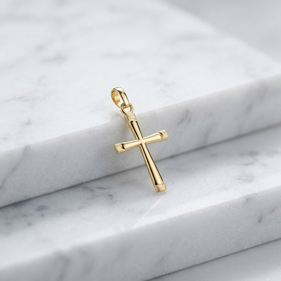 Goldener Kreuz-Anhänger Eternal mit strukturierten Enden auf weißem Marmor, hochglanzpoliert mit Öse