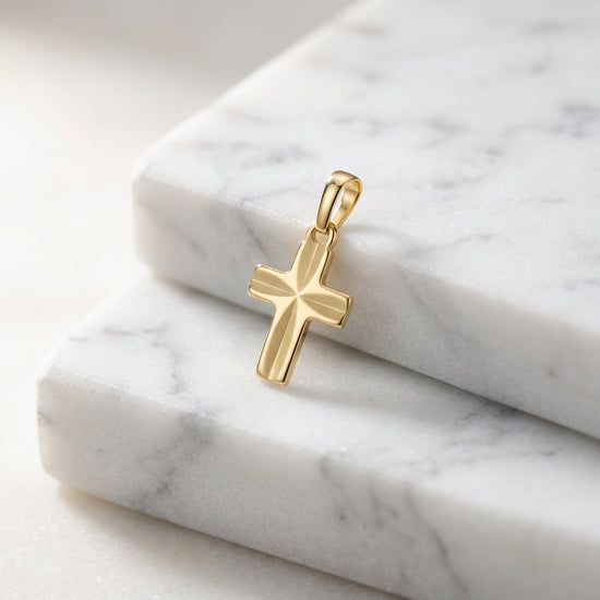 Goldener Kreuz-Anhänger Guardian mit Starburst-Muster auf weißem Marmor, poliertes Gelbgold, kleine filigrane Form