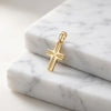 Goldener Kreuz-Anhänger Guardian mit Starburst-Muster auf weißem Marmor, poliertes Gelbgold, kleine filigrane Form