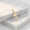 Goldener Kreuz-Anhänger Horizon mit geometrischem Design und polierten Kanten auf weißem Marmor