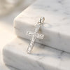 Silberner Kreuz-Anhänger mit filigranen Rankenmustern auf weißem Marmor, handgefertigt aus 925er Sterlingsilber