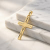 Goldener Kreuz-Anhänger mit diagonaler Liniengravur auf weißem Marmor, Edelmetall aus Pforzheimer Manufaktur