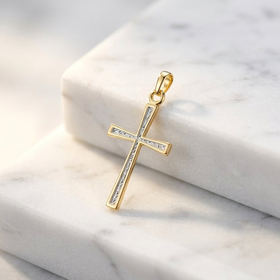 Goldener Kreuz-Anhänger Lumière mit eingelassenen Kristallen in der Mitte, auf weißem Marmor präsentiert