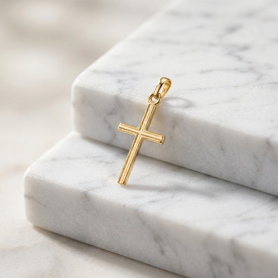 Goldener Kreuz-Anhänger Centro mit feiner Linienstruktur auf weißen Marmorblöcken