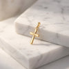 Goldener Kreuz-Anhänger mit glatter, abgerundeter Oberfläche auf weißem Marmor, handgefertigt aus massivem Gelbgold