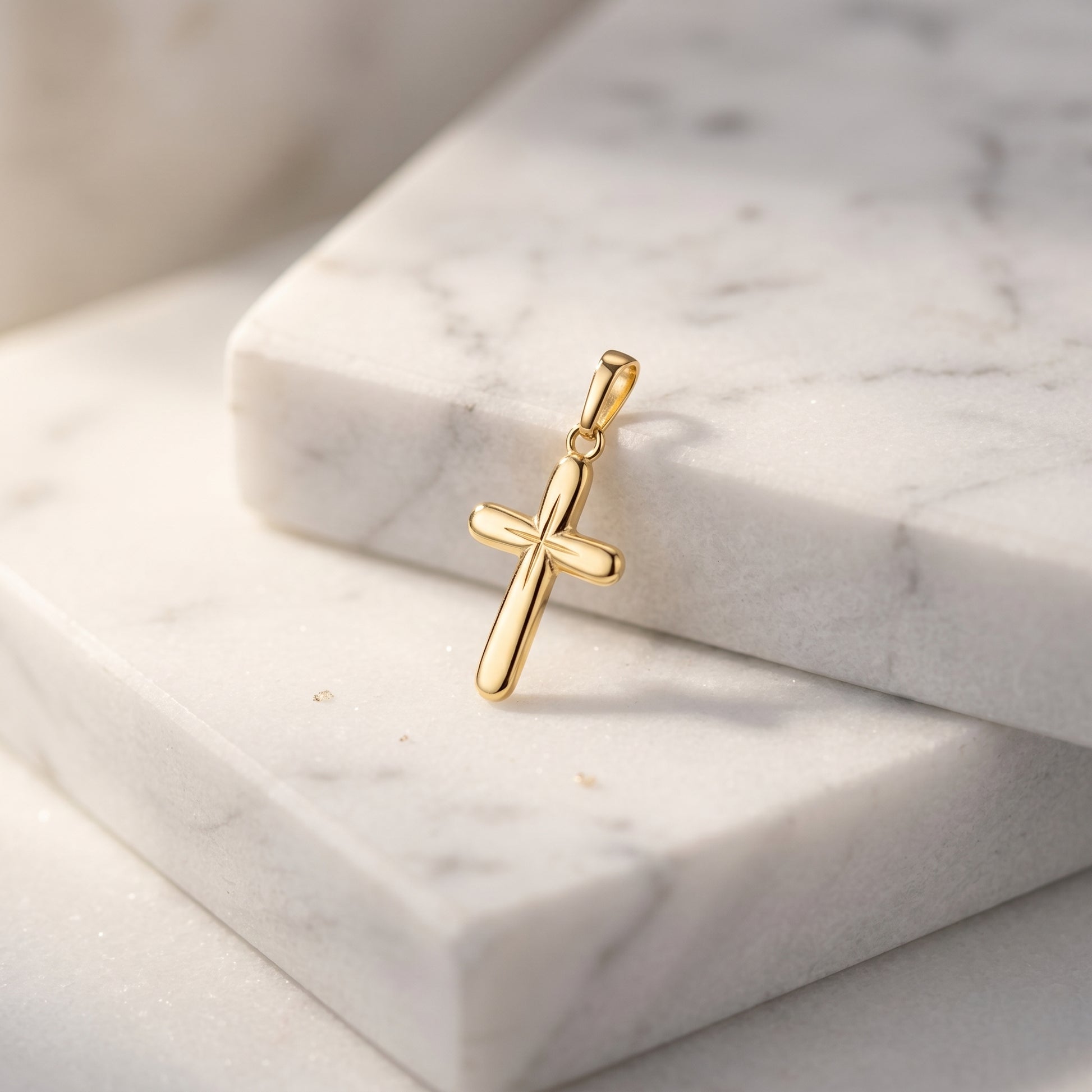 Goldener Kreuz-Anhänger mit glatter, abgerundeter Oberfläche auf weißem Marmor, handgefertigt aus massivem Gelbgold