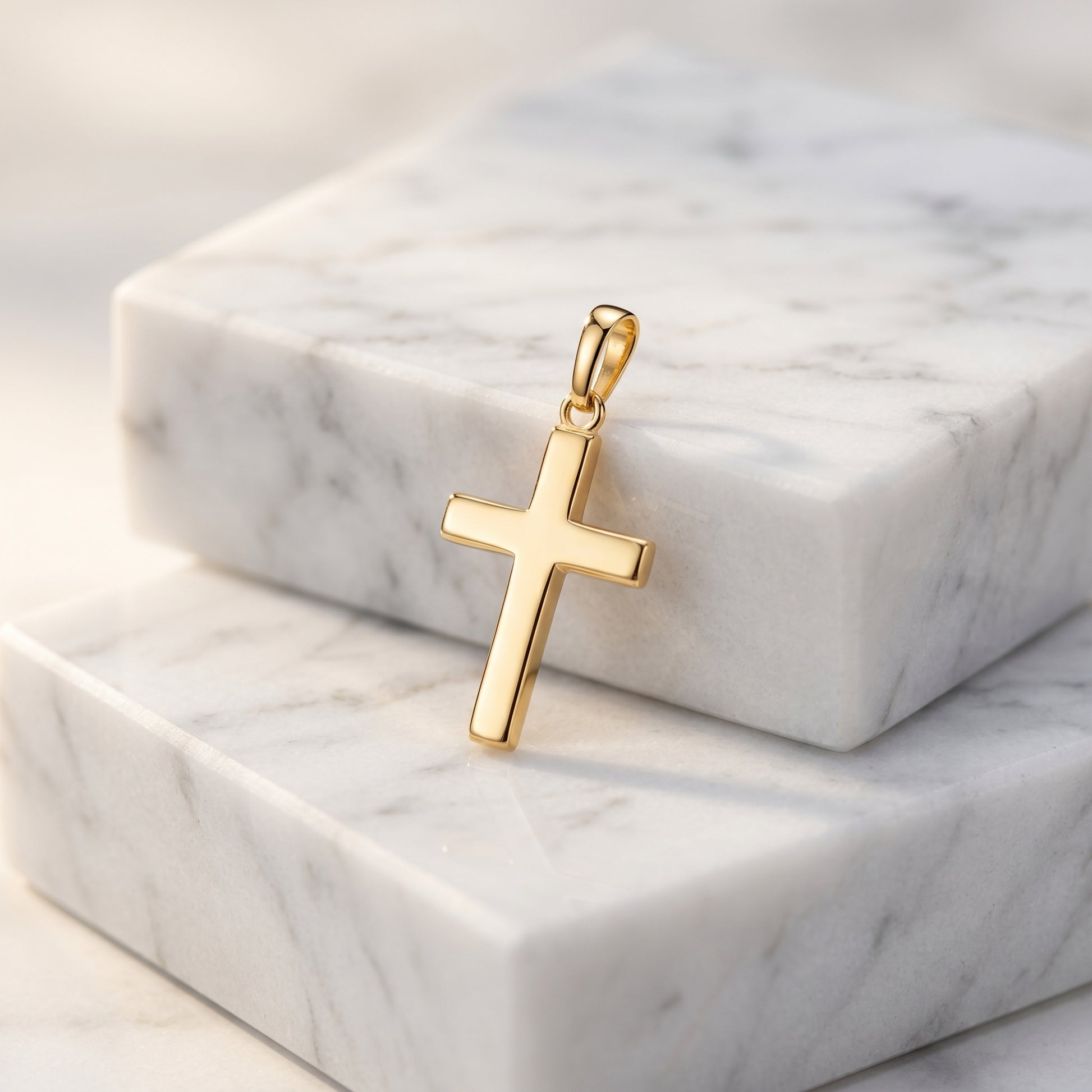Goldener Kreuz-Anhänger Essence Moyen auf weißem Marmor, polierte Oberfläche, minimalistisches Design