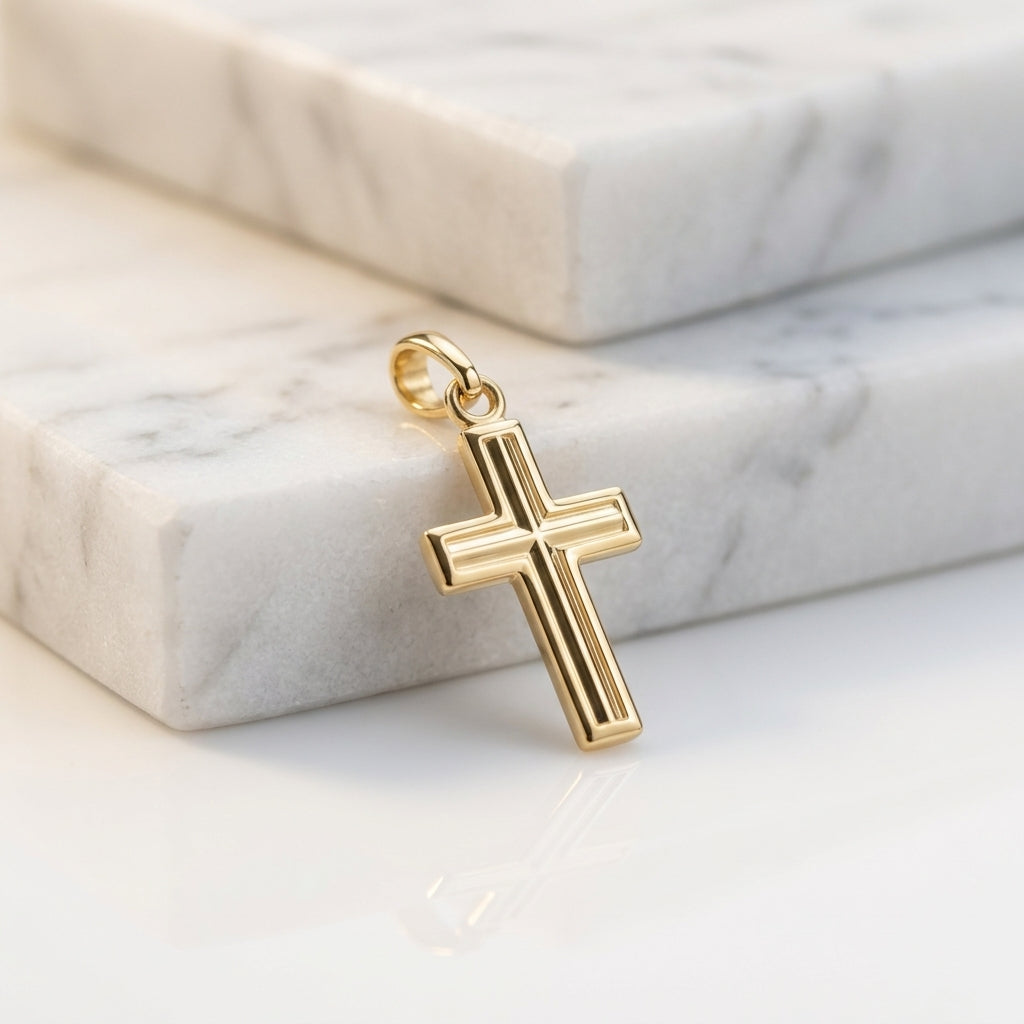 Goldener Kreuz-Anhänger mit gerillter Oberfläche und Öse auf weißem Marmor