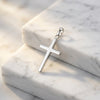 Silberner Kreuz-Anhänger Core Moyen mit polierter Oberfläche auf weißem Marmor, minimalistisches Design aus 925er Sterlingsil
