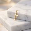 Goldener Kreuzanhänger mit Jesus-Korpus auf weißen Marmorblöcken, polierte Oberfläche, feine Details, Aurevia Manufaktur