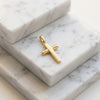 Goldener Kreuz-Anhänger Exelsis auf weißen Marmorplatten, poliertes Edelmetall mit klassischer Form und Öse