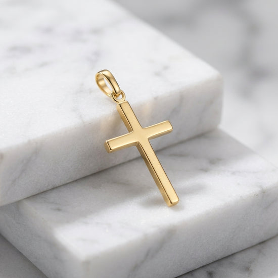 Goldener Kreuz-Anhänger Glory aus massivem Edelmetall mit polierter Oberfläche auf weißem Marmor