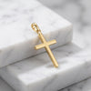 Goldener Kreuz-Anhänger Glory aus massivem Edelmetall mit polierter Oberfläche auf weißem Marmor
