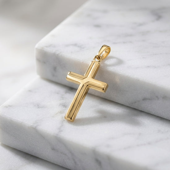 Goldener Kreuz-Anhänger Holy mit geradem Design und Öse auf weißem Marmor