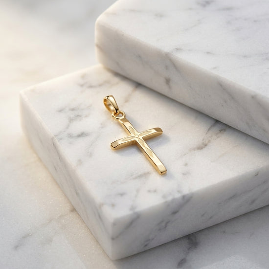 Goldener Kreuz-Anhänger mit fein graviertem Blattmuster auf weißem Marmor, handgefertigt aus 14 Karat Gold