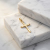 Goldener Kreuz-Anhänger mit fein graviertem Blattmuster auf weißem Marmor, handgefertigt aus 14 Karat Gold