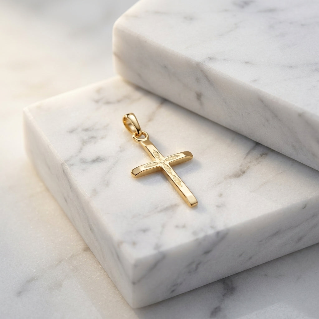 Goldener Kreuz-Anhänger mit fein graviertem Blattmuster auf weißem Marmor, handgefertigt aus 14 Karat Gold