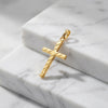 Goldener Kreuz-Anhänger mit diagonaler Rillengravur auf weißem Marmor, hochglanzpoliert mit Öse