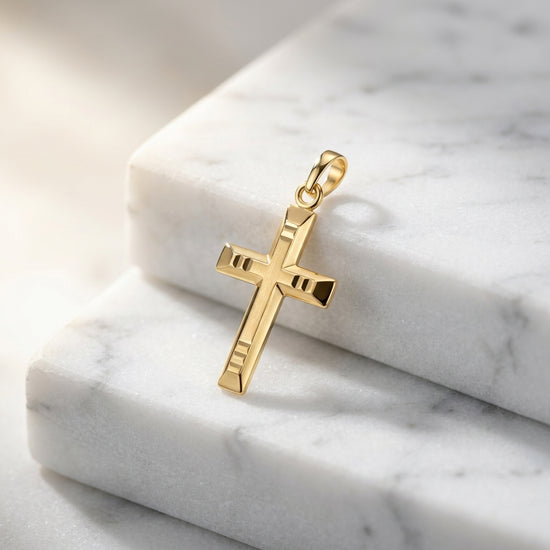 Goldener Kreuz-Anhänger mit geometrischem Muster auf weißem Marmor, hochglanzpoliert mit Öse zum Anhängen