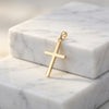 Goldener Kreuz-Anhänger Saviour auf weißem Marmor, poliertes Edelmetall mit Öse, minimalistisches Design