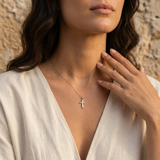 Goldener Kreuz-Anhänger an zarter Kette, getragen von Frau in weißer Bluse, Aurevia Manufaktur