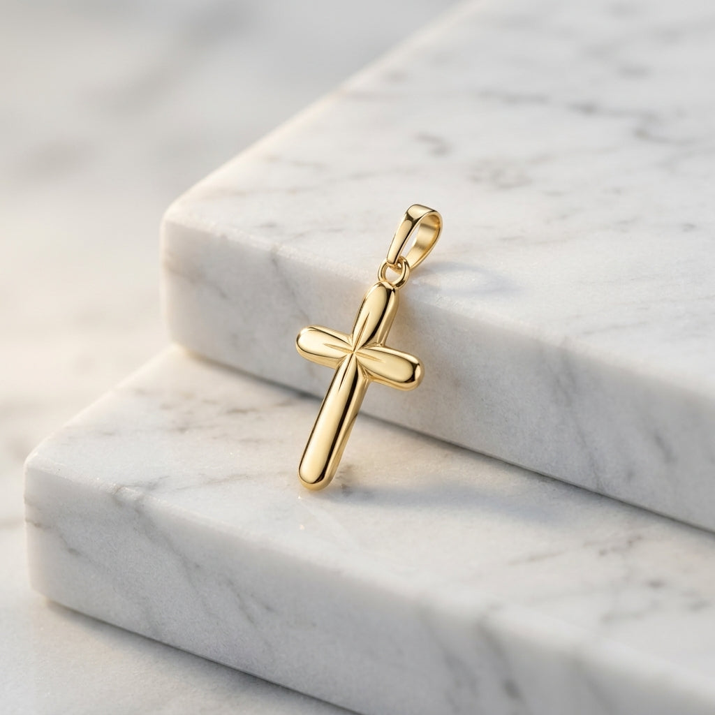 Goldener Kreuz-Anhänger Shine mit polierter Oberfläche und stilisiertem Design auf weißem Marmor